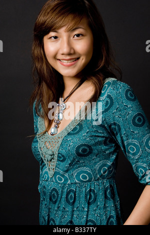 A young chinese woman in a blue green dress on black background Stock Photo