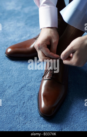 Businessman tying his shoe laces as he gets ready for work. Stock Photo
