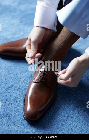 Businessman tying his shoe laces as he gets ready for work. Stock Photo