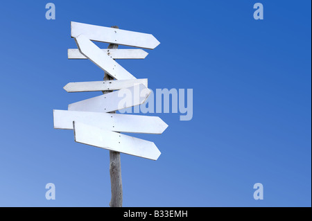 An old weathered wooden signpost with blank signs against a blue sky Stock Photo
