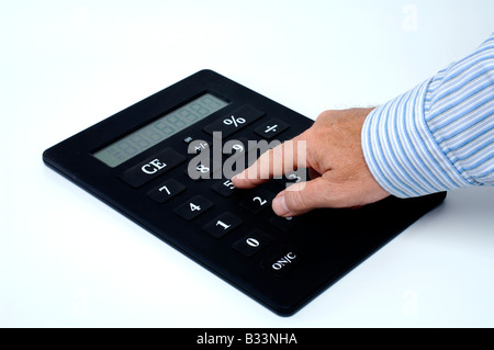 A businessman's hand doing calculations on an oversized calculator Stock Photo