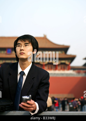 young Chinese man using his portable phone to communicate and perform business transactions. Stock Photo