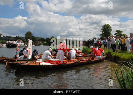 The Swan Uppers corner a sawn and her cygnets on the banks of the river Thames lined with a group of spectators Stock Photo