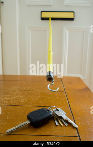 Car and house keys being stolen through letterbox by using a stick with a hook on the end Stock Photo