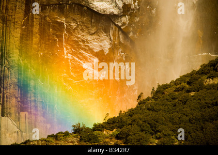 Early morning sun illuminates the spray at the base of the upper Yosemite Falls creating a rainbow of color Stock Photo