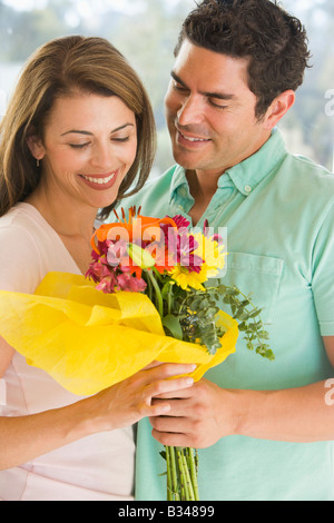 Husband giving wife flowers and smiling Stock Photo