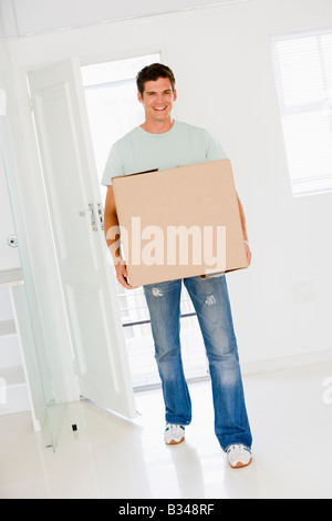 Man with box moving into new home smiling Stock Photo