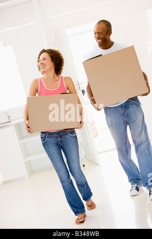 Couple with boxes moving into new home smiling Stock Photo