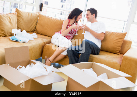 Couple relaxing with champagne by boxes in new home smiling Stock Photo
