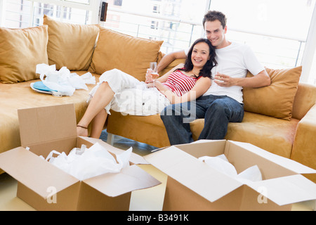 Couple relaxing with champagne by boxes in new home smiling Stock Photo