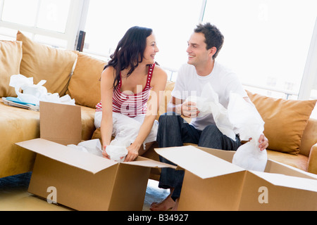 Couple unpacking boxes in new home smiling Stock Photo