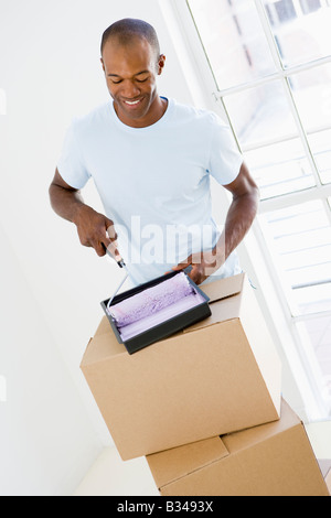 Man with roller and paint in new home smiling Stock Photo