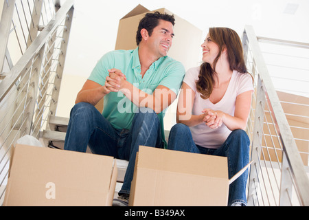 Couple sitting on staircase with boxes in new home smiling Stock Photo