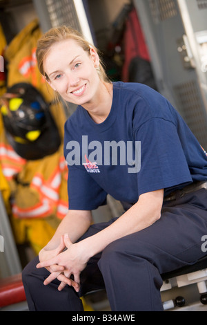 Firewoman sitting on bench in fire station locker room Stock Photo