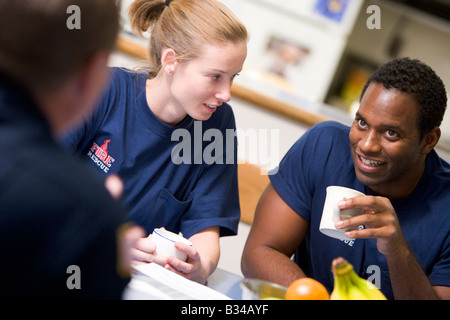Three firefighters in break room drinking coffee and talking (selective focus) Stock Photo