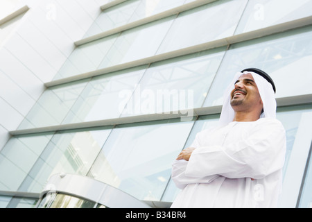 Businessman standing outdoors by building smiling Stock Photo