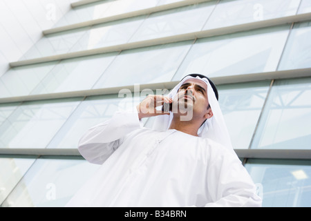 Businessman standing outdoors by building on cellular phone (selective focus) Stock Photo