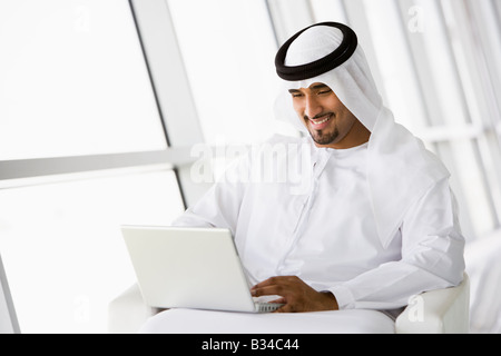 Man indoors with laptop smiling (high key/selective focus) Stock Photo