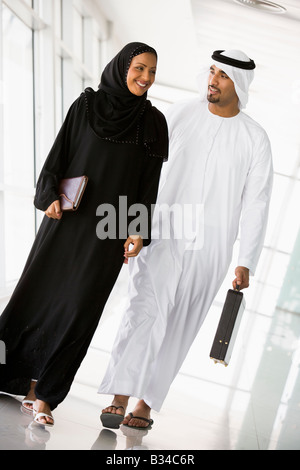 Two businesspeople walking in a corridor and smiling (high key/selective focus) Stock Photo