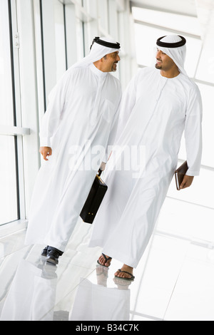 Two businessmen walking in a corridor talking and smiling (high key/selective focus) Stock Photo