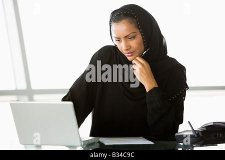 Businesswoman in office with laptop thinking (high key/selective focus) Stock Photo