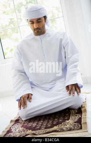 Man in turban praying on mat (high key) Stock Photo