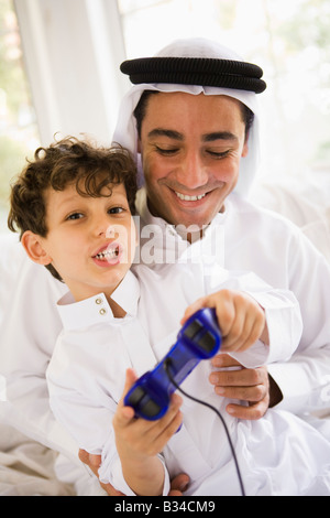 Father and son in living room playing video games and smiling (high key/selective focus) Stock Photo