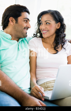 Couple in living room with laptop smiling (high key/selective focus) Stock Photo