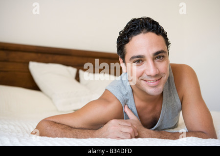 Man relaxing on bed in bedroom smiling (selective focus) Stock Photo