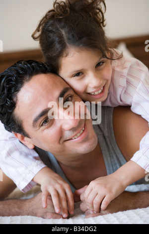 Father and daughter girl relaxing on bed in bedroom smiling (selective focus) Stock Photo