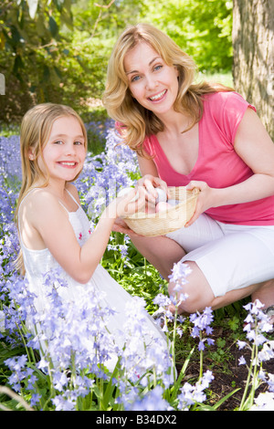 Mother and daughter on Easter looking for eggs outdoors smiling Stock Photo