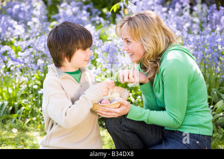 Mother and son on Easter looking for eggs outdoors smiling Stock Photo