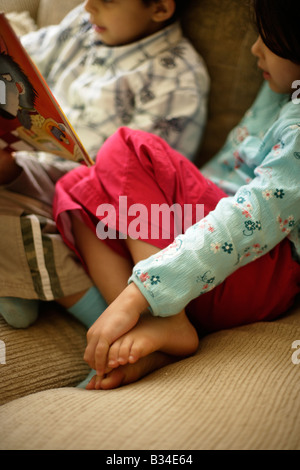 Boy aged six reads a story to his little sister aged five Stock Photo