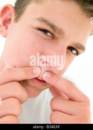 Teenage boy popping zit on face Stock Photo