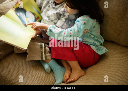 Boy aged six reads a story to his little sister aged five