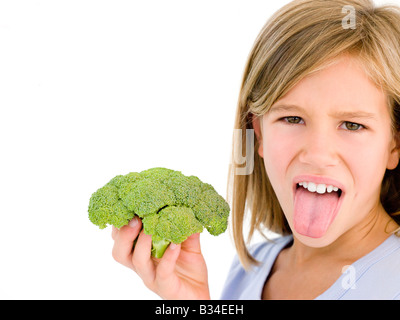 Young girl holding broccoli and sticking tongue out Stock Photo