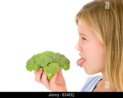 Young girl holding broccoli and sticking tongue out Stock Photo