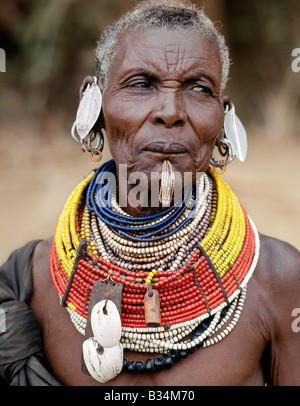 Kenya, Lodwar District, Lokori. An old Turkana woman wearing all the finery of her tribe.In a hole pierced below her lower lip, Stock Photo