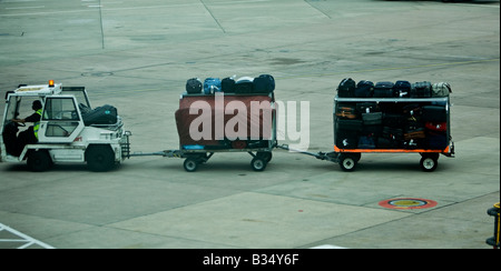 Baggage handler  moveing luggage at airport air side British Airport Manchester International Stock Photo