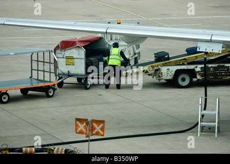 Baggage handler moveing luggage  onto aircraft - airport air side UK GB British Airport Manchester International Stock Photo