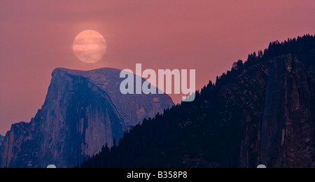 A full moon rises over Half Dome at sunset with smoky skies, Yosemite National Park, California, USA Stock Photo