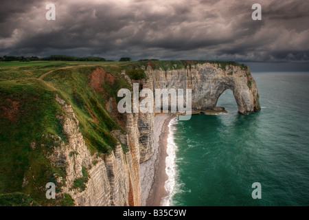 A moody representation with an incoming storm in the background of the cliff known as La Manneporte near to Etretat, Normandy Stock Photo