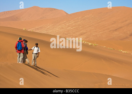 Visitors hike among sand dunes in Sossusvlei Namibia Africa Stock Photo