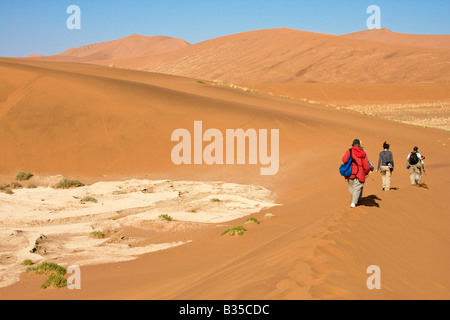 Visitors hike among sand dunes in Namib Naukluft Park at Sossusvlei in Namibia Africa