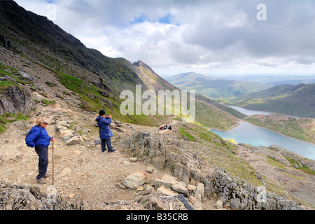Two people resting and admiring the view from the Pyg Track towards Llyn Glaslyn and Llyn Llydaw on Mount Snowdon Stock Photo