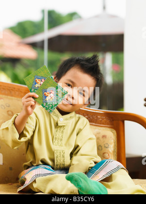 Malay boy holding two green packets up Stock Photo