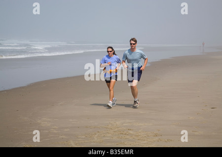 Joggers run on the wide sandy beach near Manzanita Beach Oregon Stock Photo