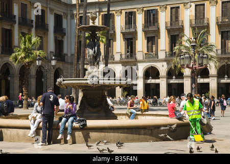 SPAIN Barcelona People sit along fountain in Placa Reial Neoclassical square plaza woman sweeping litter and debris Stock Photo