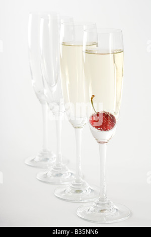 Champagne flutes, two filled with champagne, one with a cherry floating in it Stock Photo