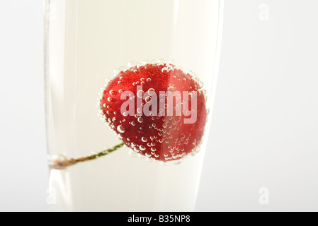 Cherry floating in glass of champagne, close-up Stock Photo
